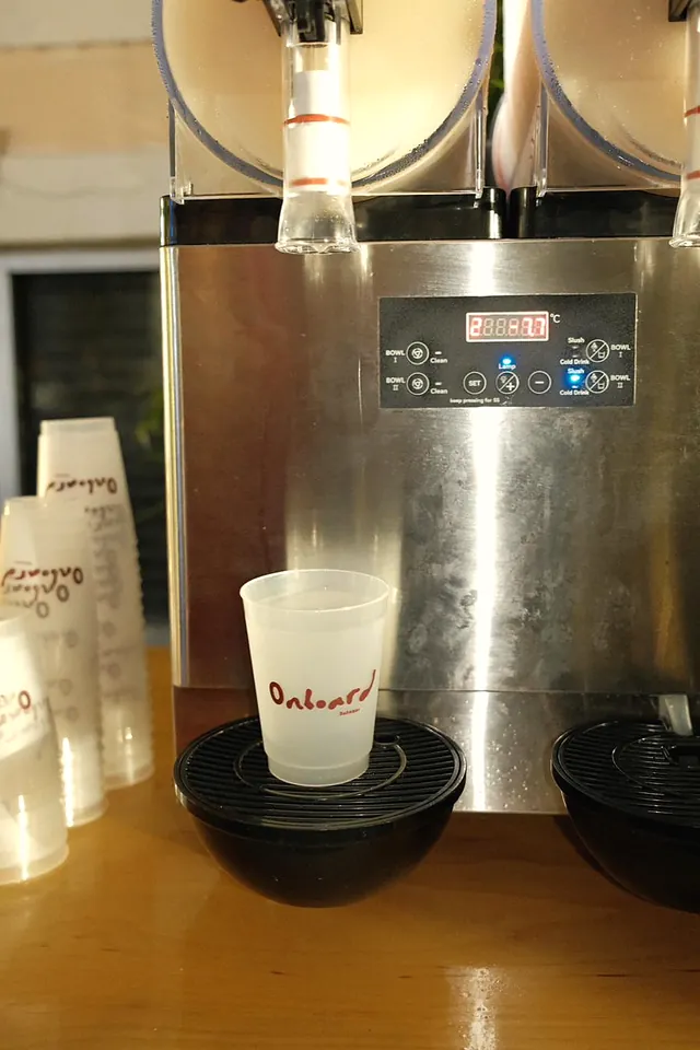 A frozen drink in an Onboard printed cup under the slush machine
