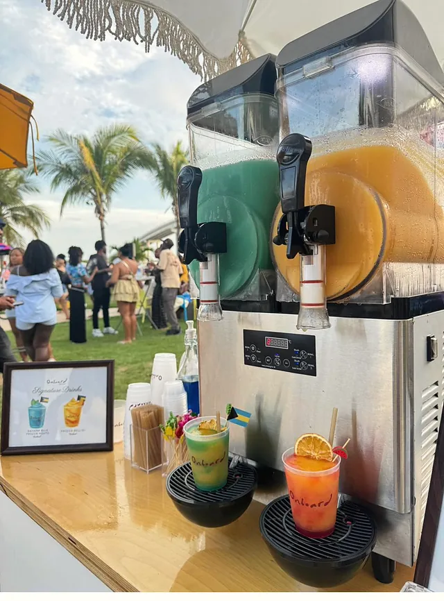 The slush machine pouring green and orange frozen drinks at an outdoor party